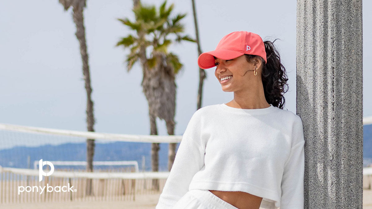 Woman wearing coral Ponyback ponytail hat on the beach